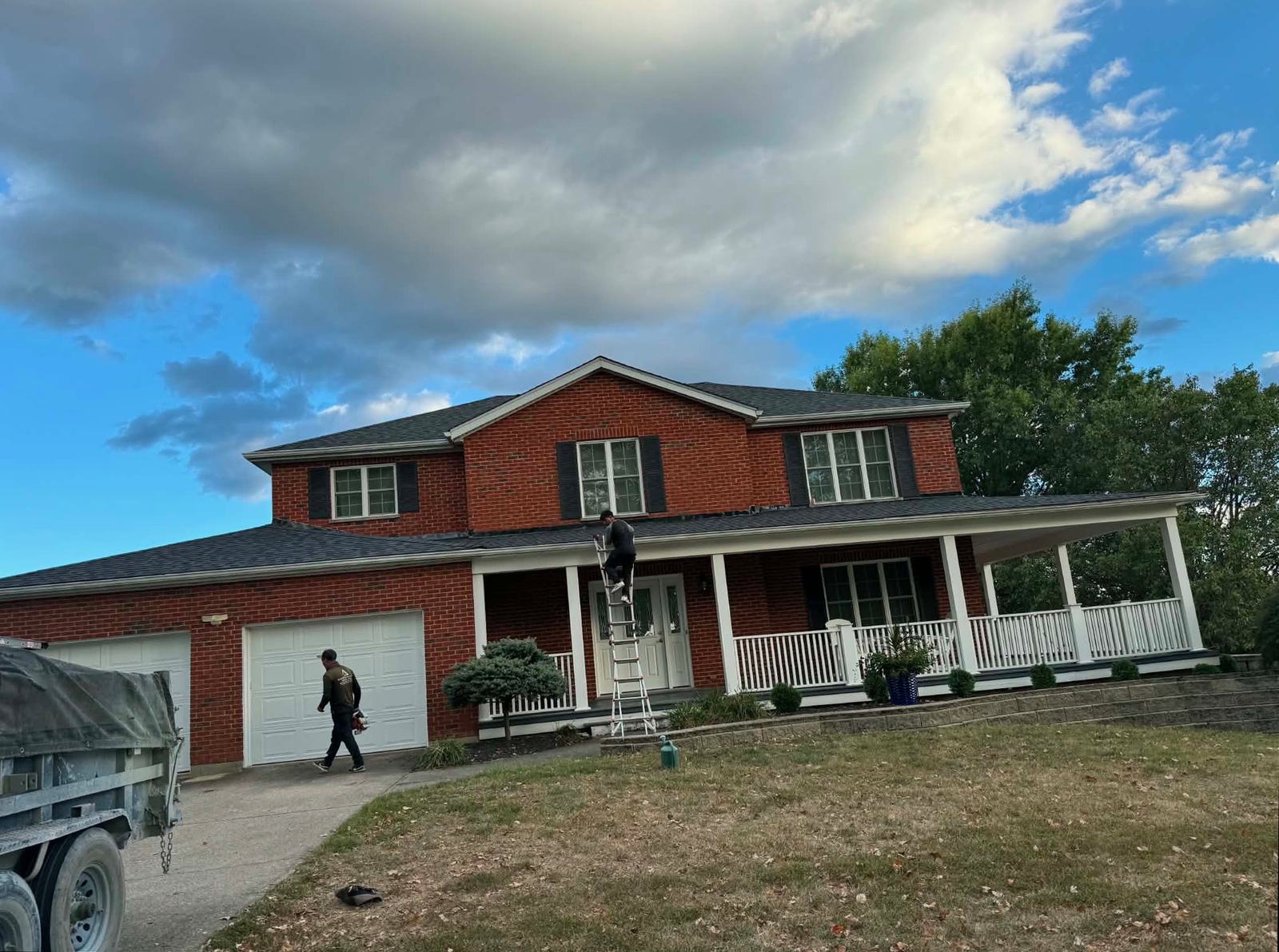 Crew installing a new architectural shingle roof on a two-story brick home